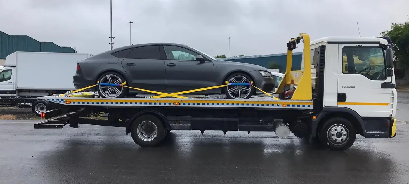 A grey hatchback strapped on a flatbed truck