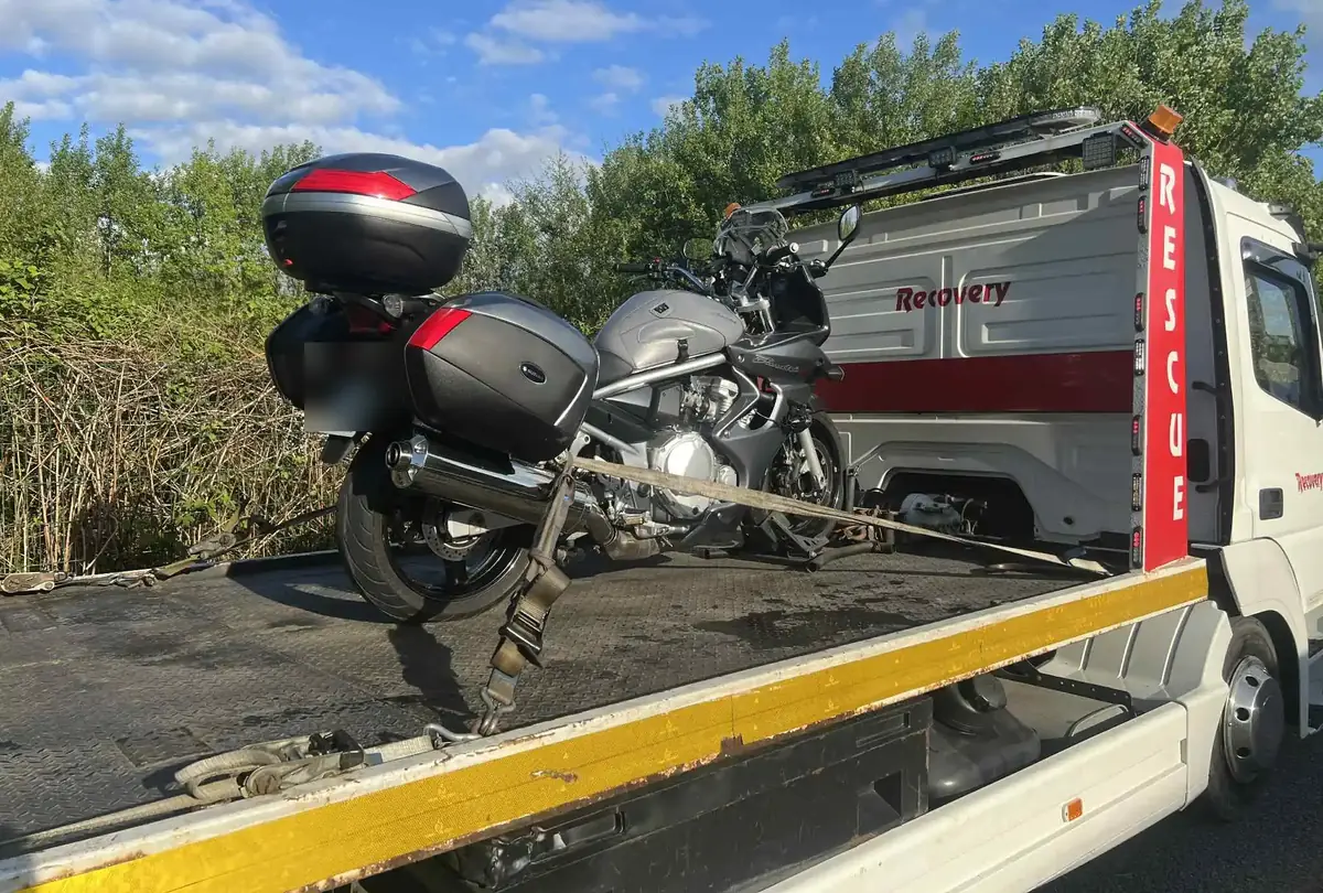 A loaded touring motorbike secured on the deck of a recovery truck