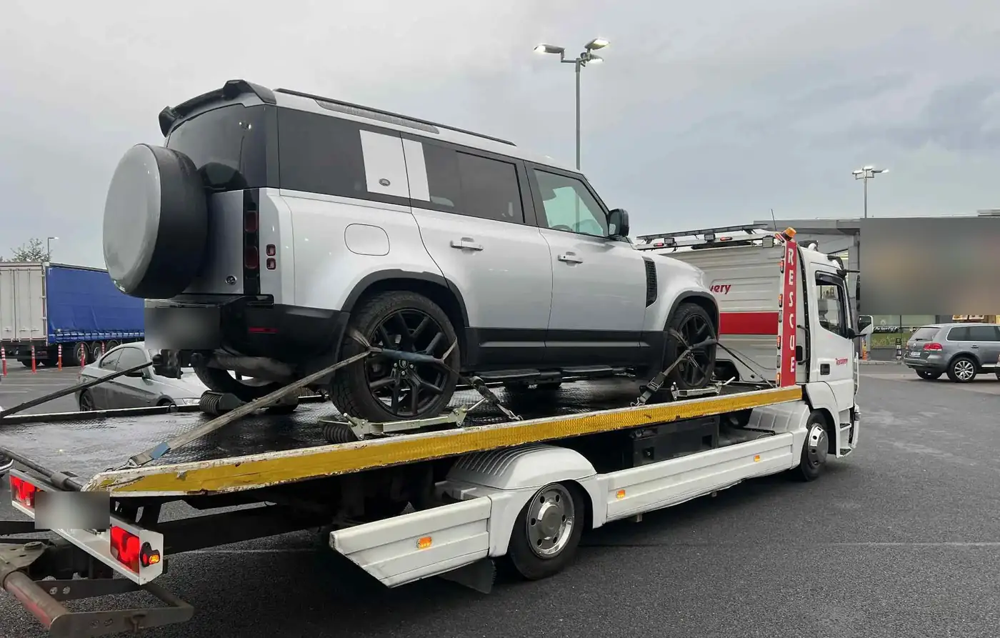 A Land Rover Defender strapped down on a recovery truck
