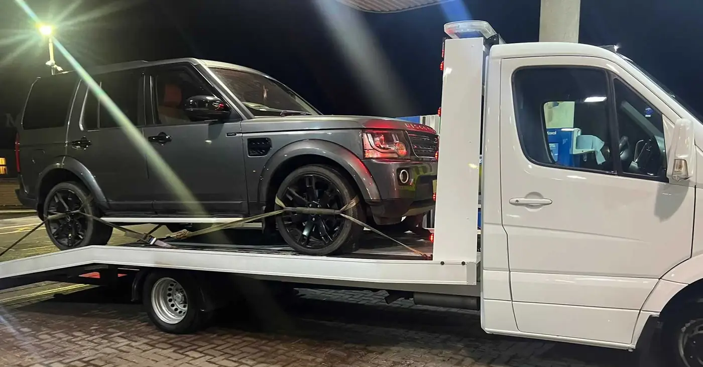 A Land Rover loaded at a forecourt at night