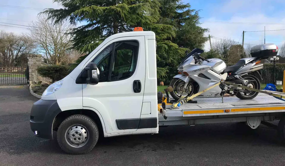 A silver touring motorbike strapped upright on a CC Recovery flatbed