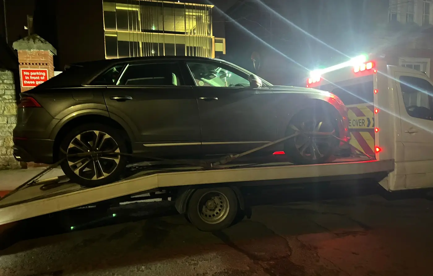 A dark SUV going up the ramp at night