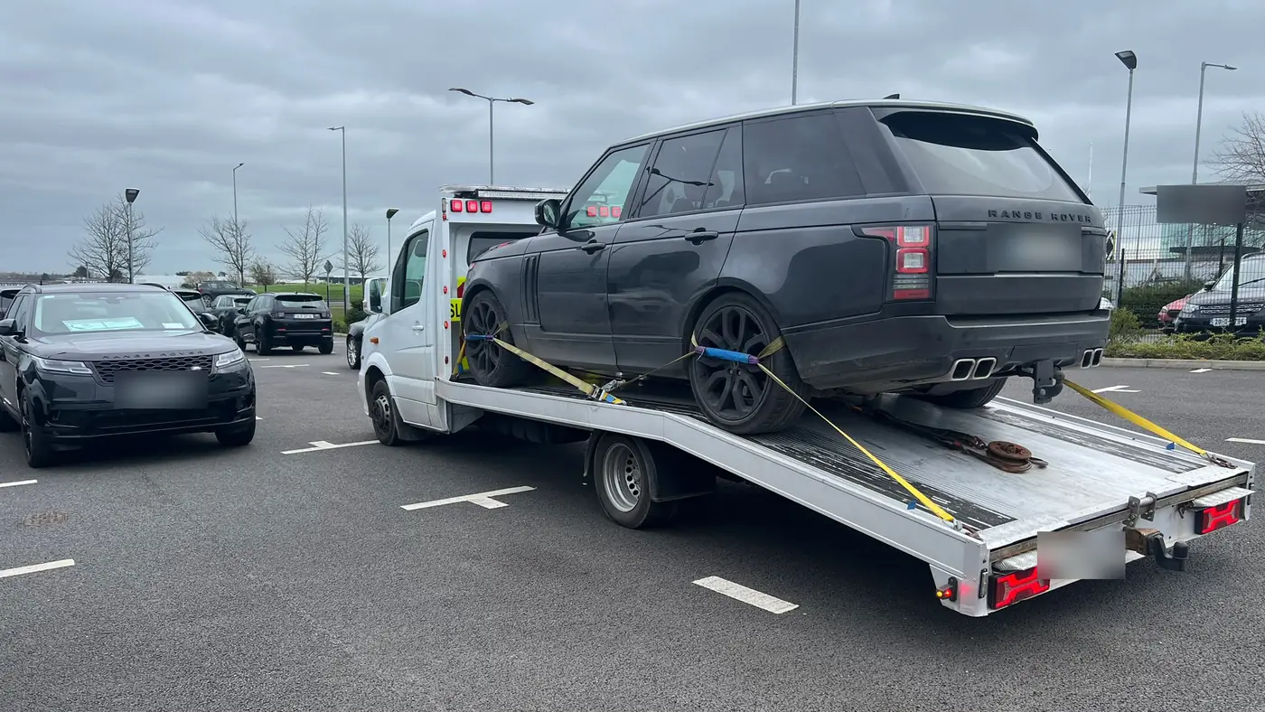 A black 4x4 strapped down on a white CC Recovery flatbed