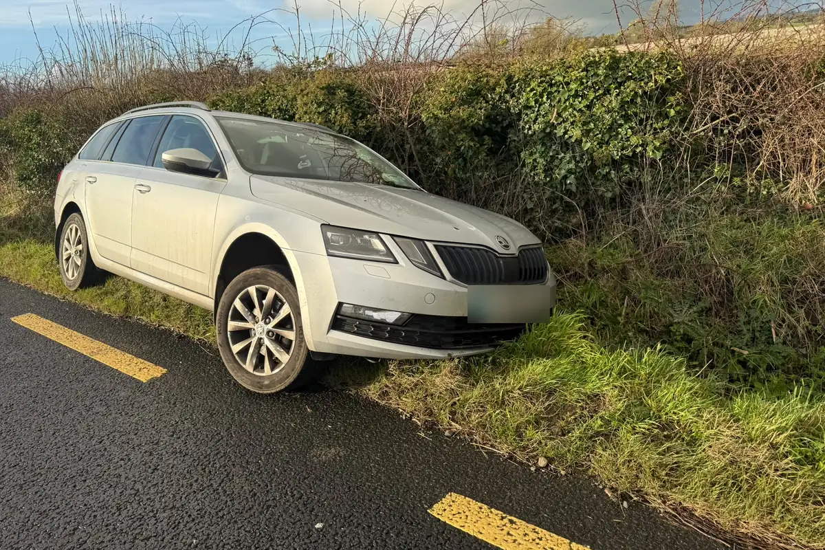 A silver estate car with its front wheels down in a roadside ditch on a Meath country road