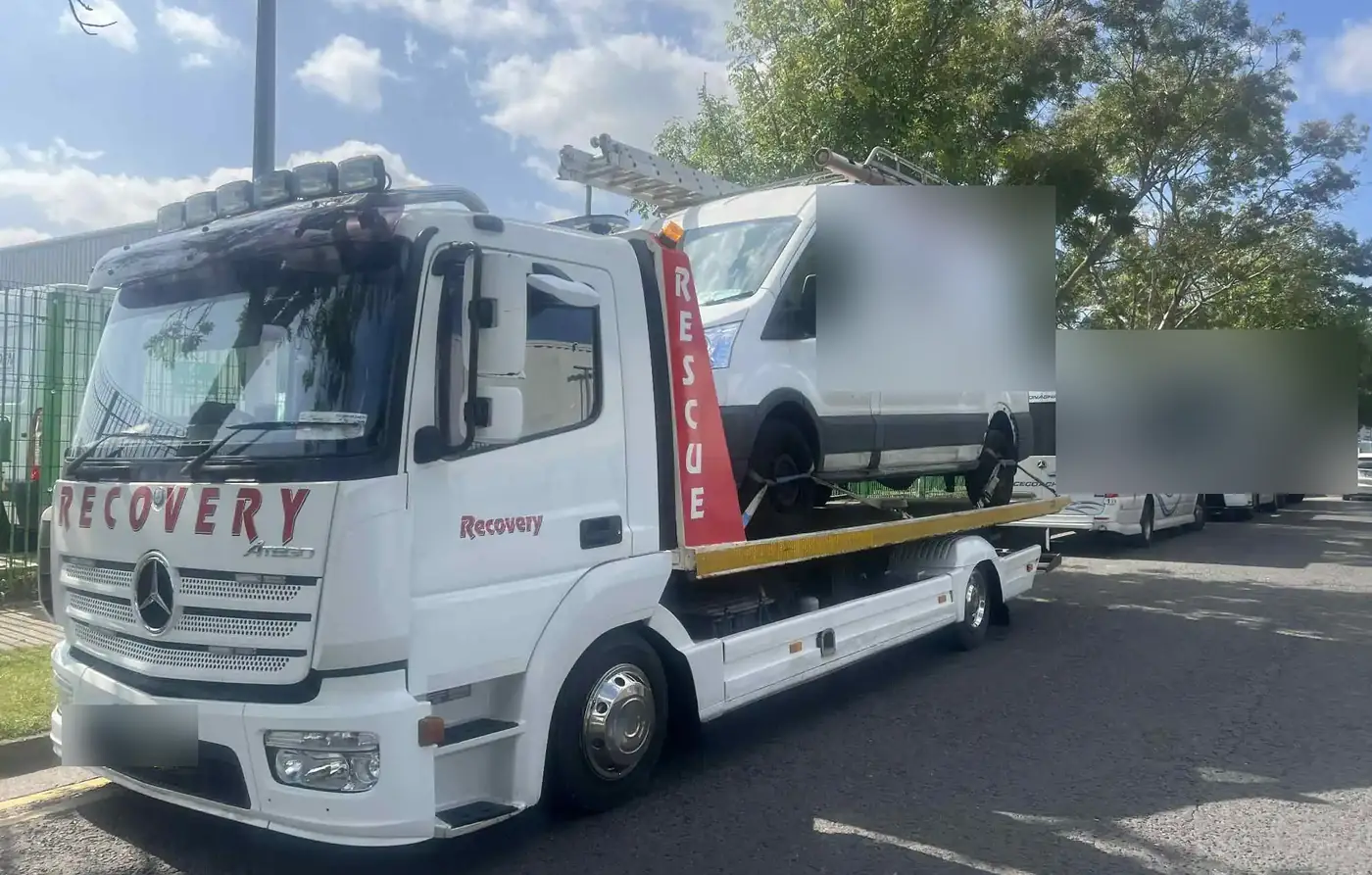 A large van on the back of a CC Recovery tow truck